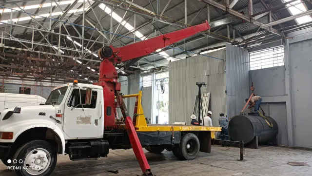 Camión grúa hidráulica trabajando dentro de una bodega industrial