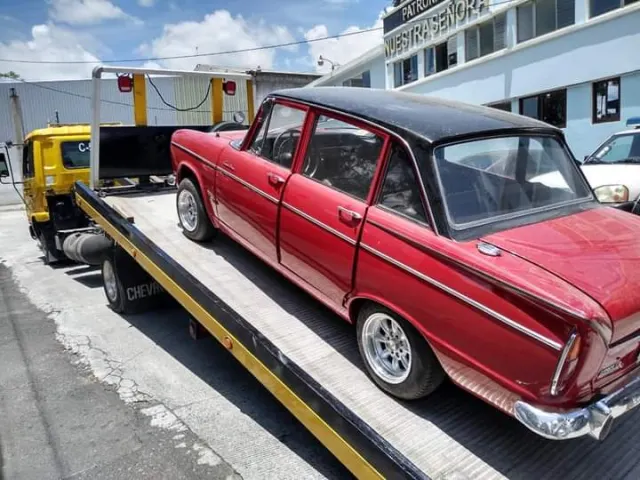 Grúa de plataforma subiendo un automóvil clásico rojo